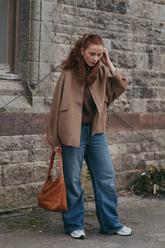 a lady in a brown tencel wool jacket and a pair of jeans
